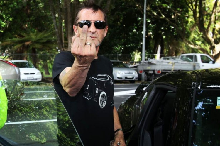 TAURANGA, NEW ZEALAND - NOVEMBER 26: AC/DC drummer Phil Rudd gestures to members of the media after leaving Tauranga District Court after appearing in court after being charged with threatening to kill and possession of meth and marijuana at Tauranga District Court on November 26, 2014 in Tauranga, New Zealand. Phil Rudd was ACDC's drummer from 1975 to 1983. (Photo by Joel Ford/Getty Images)